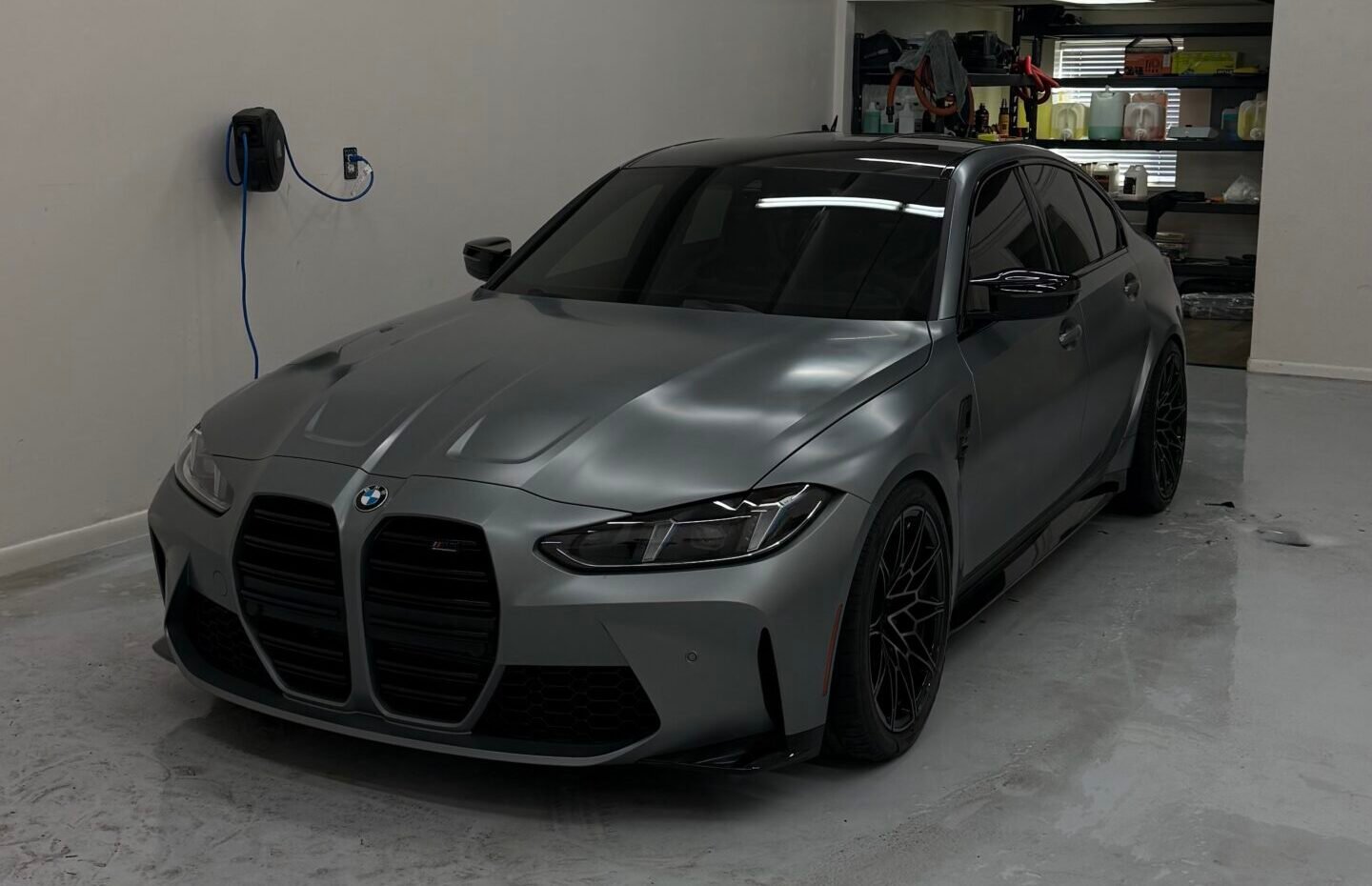 Deep metallic blue luxury car with light dirt and water spots on hood and headlight before detailing